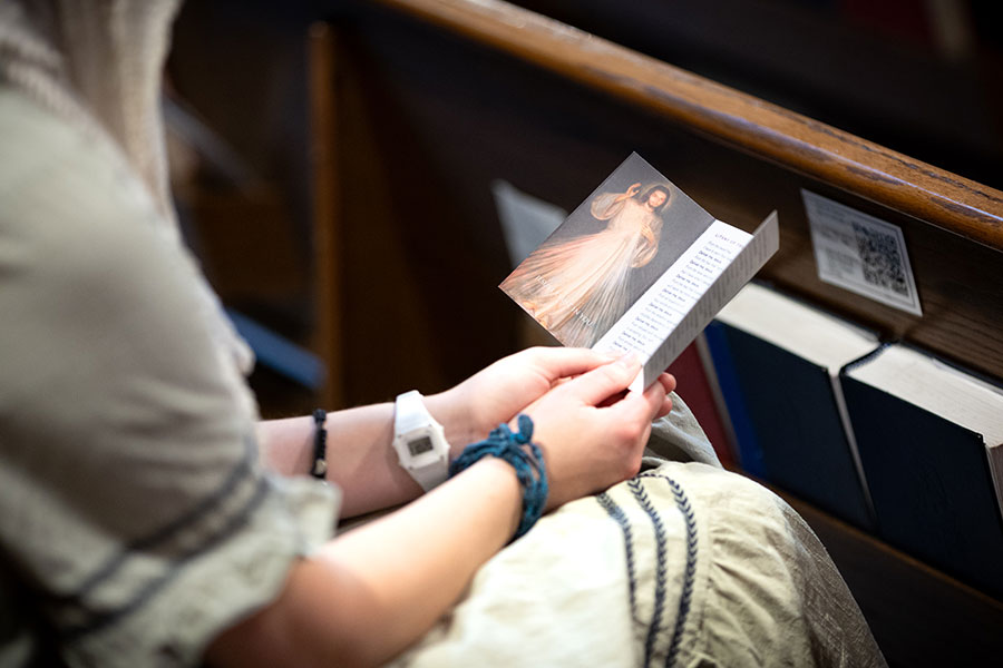 young woman prays using a prayer card